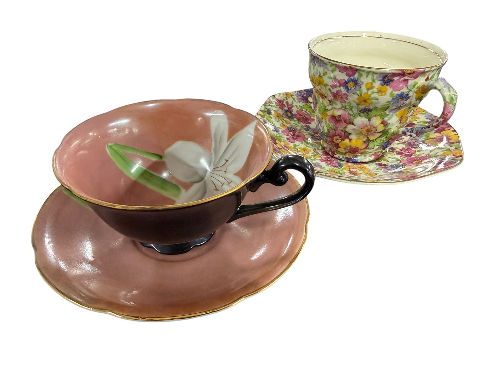 Pair of Cups and Saucers: Pair of Cups and Saucers. A James Kent Du Barry Floral Chintz pattern cup and saucer, from James Kent Ltd, Longton, England, and a Trimont hand painted cup and saucer, featuring a lilly on a mauve
