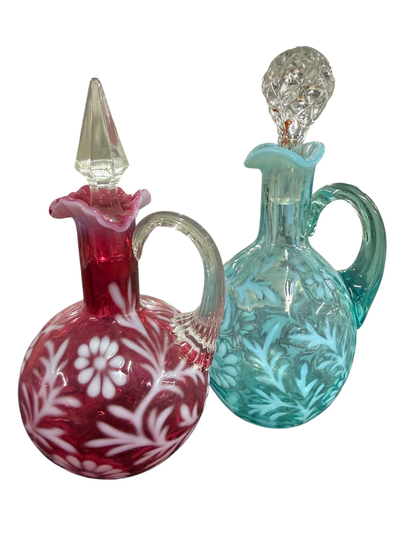 A Pair of Fenton Fern & Daisy Cruets: A Pair of Fenton Fern & Daisy Cruets. One in Cranberry, and one in blue. The stopper in the blue cruet does not appear to be original.