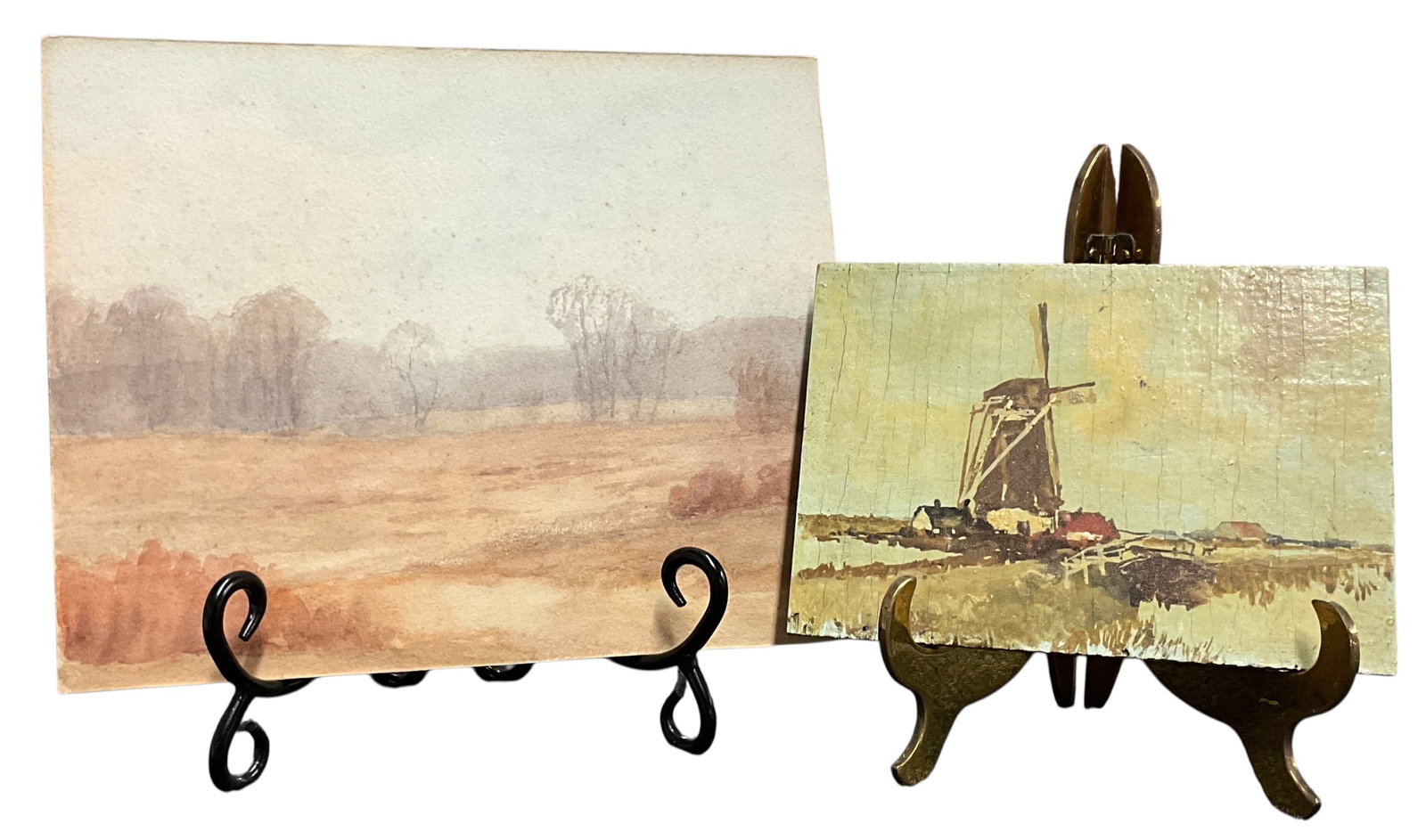 Pair of Vintage Landscape Paintings – Watercolor & Windmill Scene on Board: A pair of vintage landscape paintings including a soft-toned watercolor countryside scene and a rustic windmill composition on panel. Age-related toning, spotting, and surface wear present.