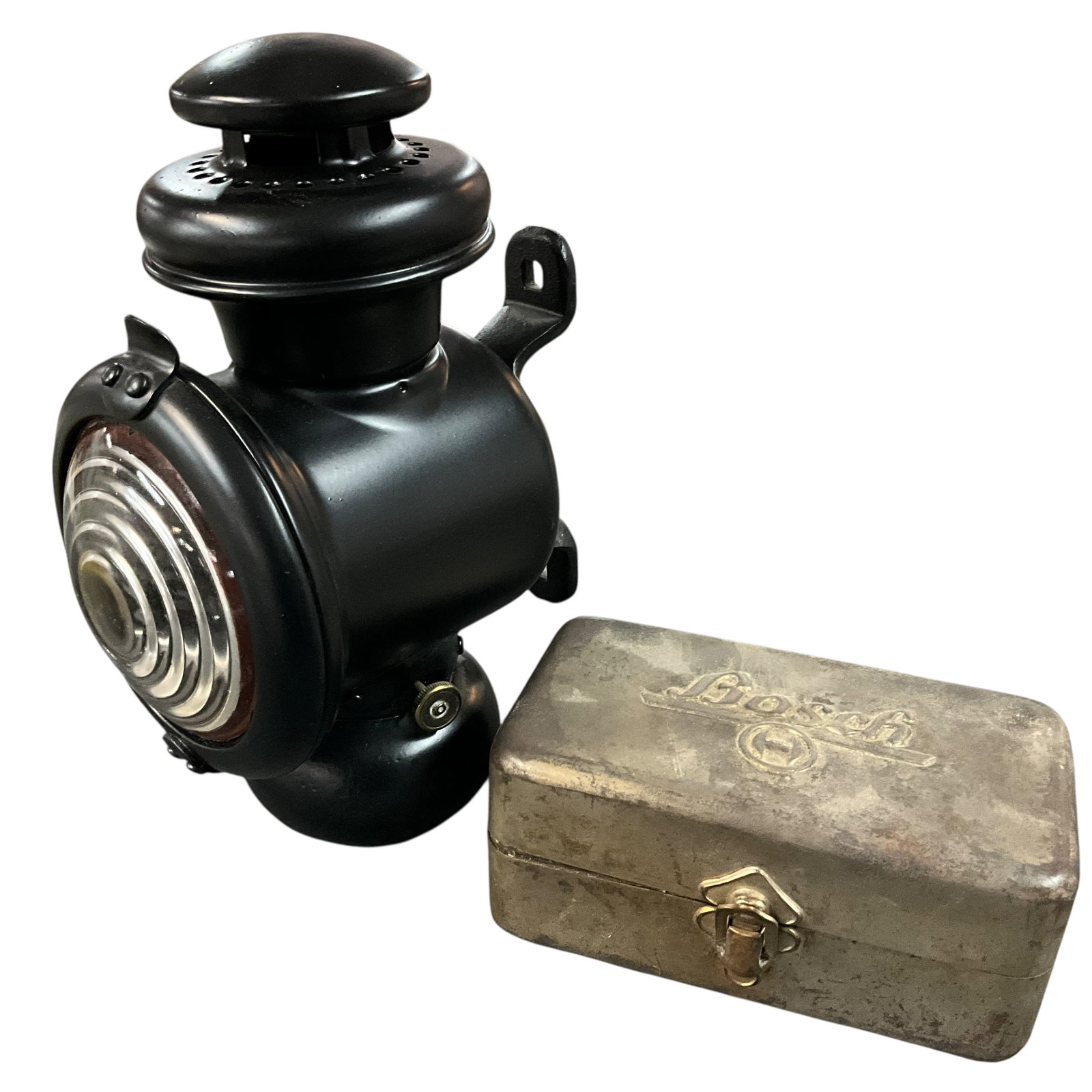 Ford Model T Headlamp/Lantern & “Bosch?? Metal Storage Tin: Ford Model T headlight with black metal body and bullseye glass lens, paired with a metal storage tin embossed “Bosch” on the lid. The lamp features a hinged front access door and mounting bra