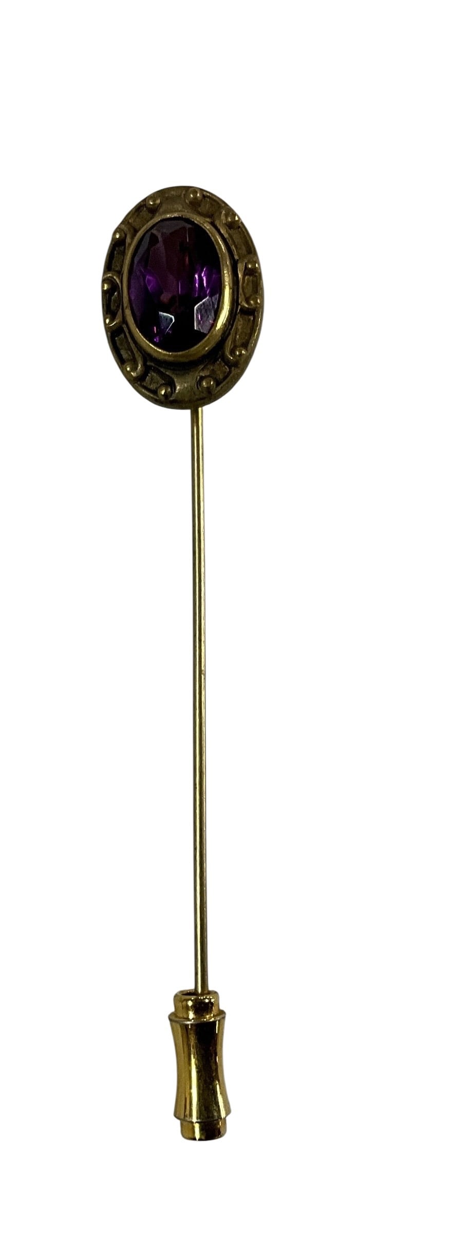 Antique Gold Tone Stick Pin with Purple Glass Stone: Antique stick pin featuring an oval faceted purple glass stone set in a decorative gold tone bezel with raised detailing. The mount has a classic Victorian-inspired design with a long pin shaft and pr