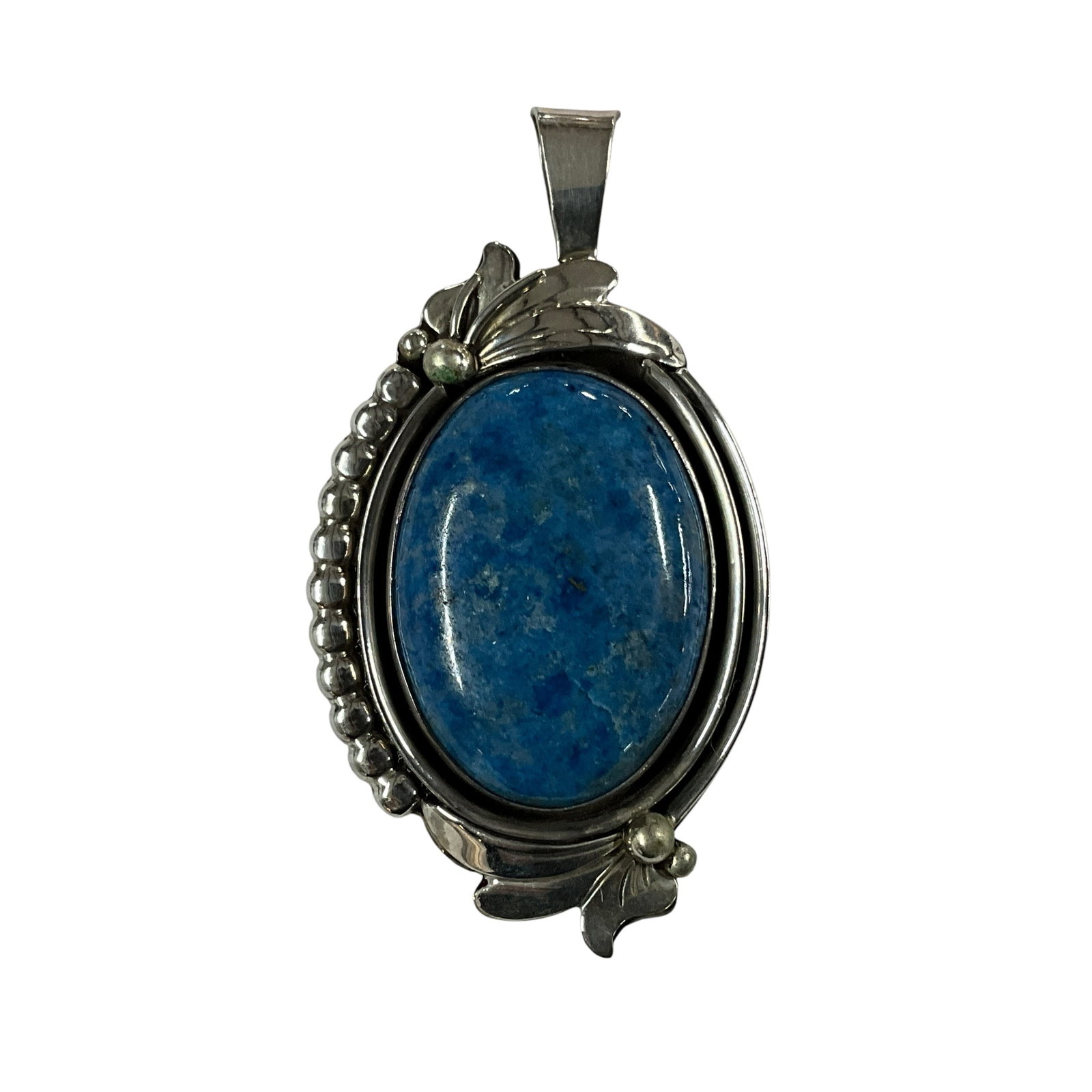 Sterling Silver Blue Stone Pendant by Oscar Betz (Navajo): Striking sterling silver pendant featuring a large oval cabochon blue stone, likely turquoise or sodalite, set in a handcrafted bezel. The piece is accented with traditional Navajo-style silverwork in