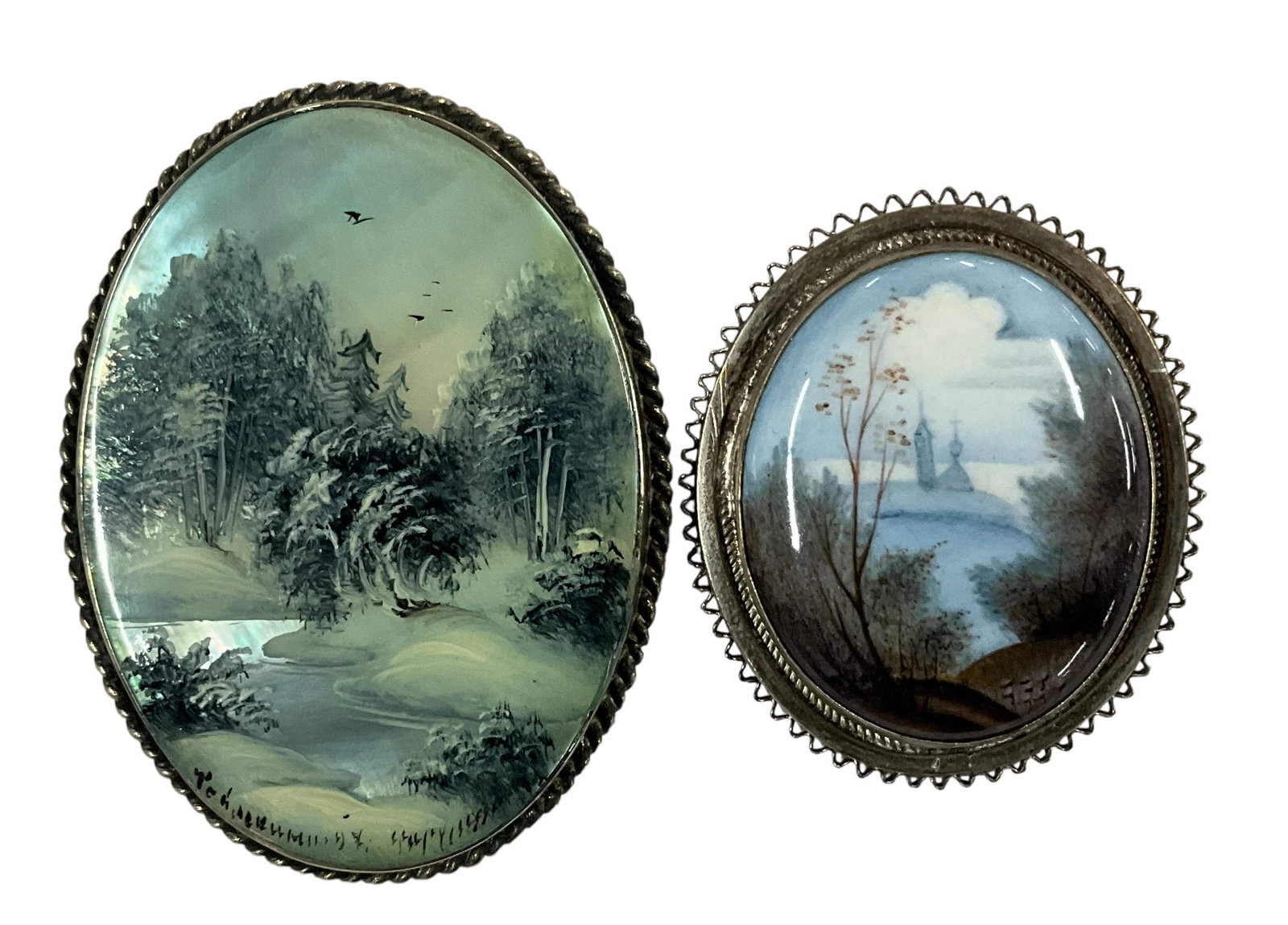 Vintage Hand-Painted Porcelain Scenic Brooches (2): Pair of vintage hand-painted porcelain brooches featuring finely detailed scenic landscapes under domed glass or glazed finishes. The larger oval brooch depicts a serene Asian-inspired landscape with 