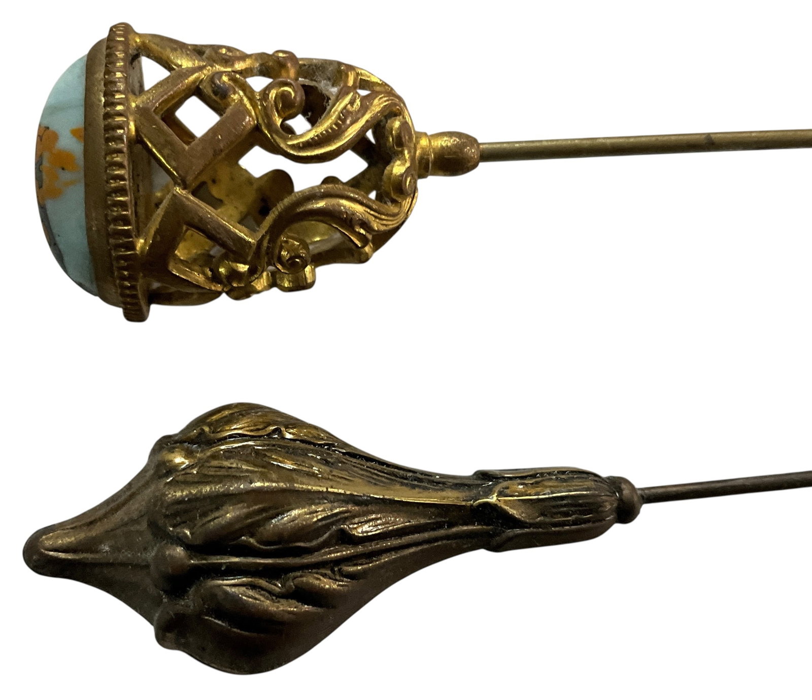 Pair of Antique Gold-Tone Hat Pins with Decorative Finials, Including Stone-Set Openwork Example: Group of two antique hatpins featuring decorative gold-tone mounts in contrasting designs. One example features an ornate openwork mount set with an oval cabochon stone displaying mottled light blue a