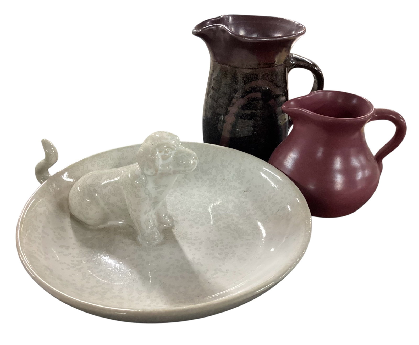 Assorted Studio Pottery Pitchers and Ceramic Dog Dish: Decorative grouping featuring two handled studio pottery pitchers including a burgundy glazed pitcher marked --Snowy Mountains Pottery-? and a taller dark glazed pitcher with abstract decoration, toge