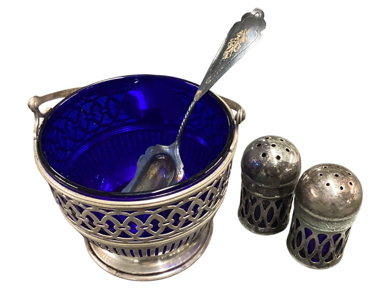 Sterling Silver & Silver Plate Cobalt Glass Condiment Set with Spoon: Vintage condiment service set featuring a sterling silver mounted cobalt blue glass bowl with pierced silver overlay and swing handle, accompanied by matching silver plate cobalt glass salt and pepper