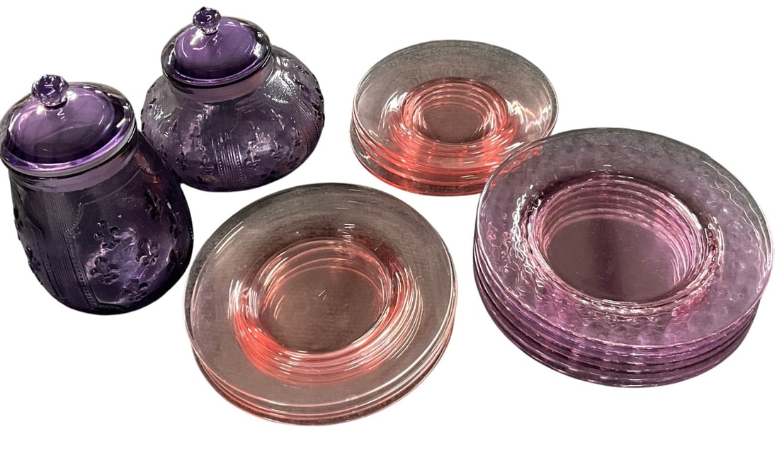 Group of Vintage Purple and Pink Depression Glass Tablewares: Decorative grouping of vintage colored glass tablewares including two purple covered glass jars or powder containers with embossed fleur-de-lis decoration, together with pink depression glass plates