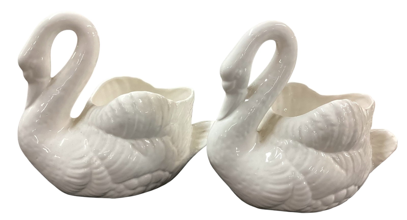 Pair of White Ceramic Swan Planters / Cachepots: Lot includes a matching pair of glossy white ceramic swan-form planters or cachepots. Each features a stylized swan body with molded feather detailing, curved neck, and open-top planter cavity. Pieces