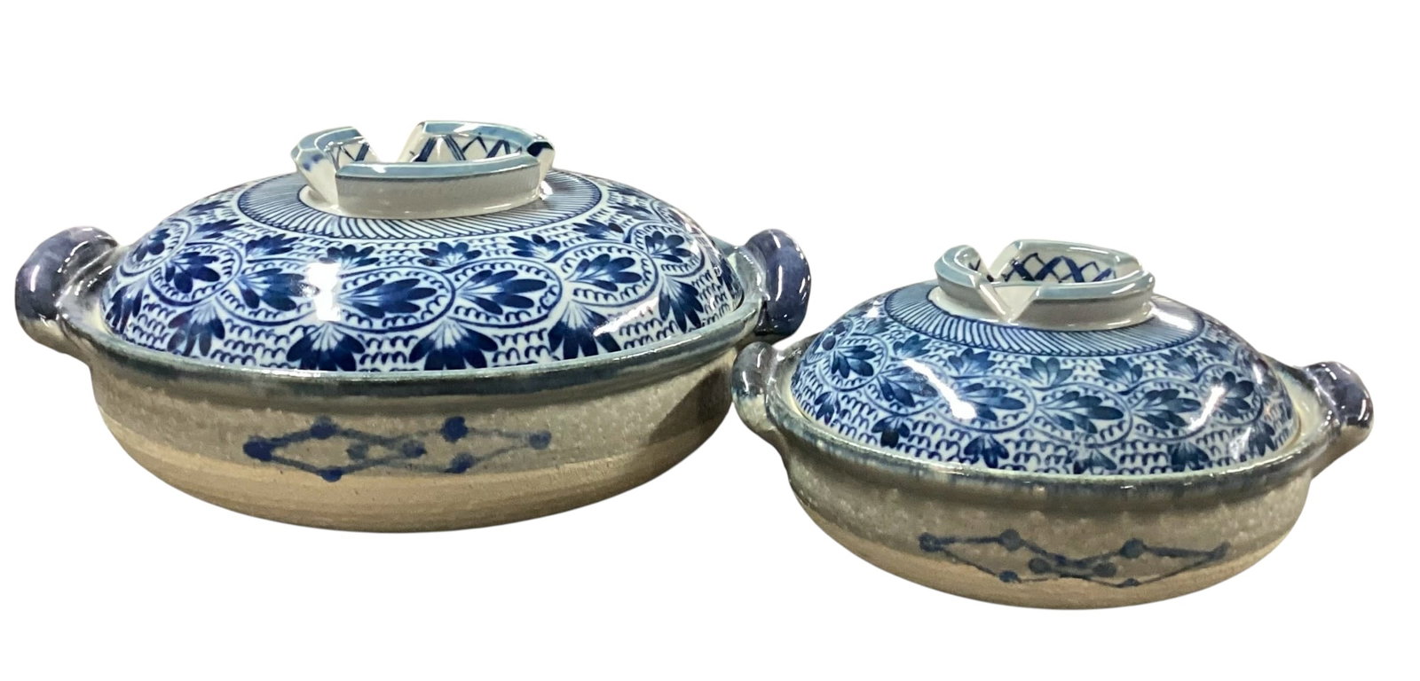Pair of Blue & White Asian-Style Covered Ceramic Serving Dishes: Lot includes two coordinating blue and white Asian-style ceramic covered serving dishes or casserole bowls in graduated sizes. Each features richly detailed floral and geometric decoration in cobalt b