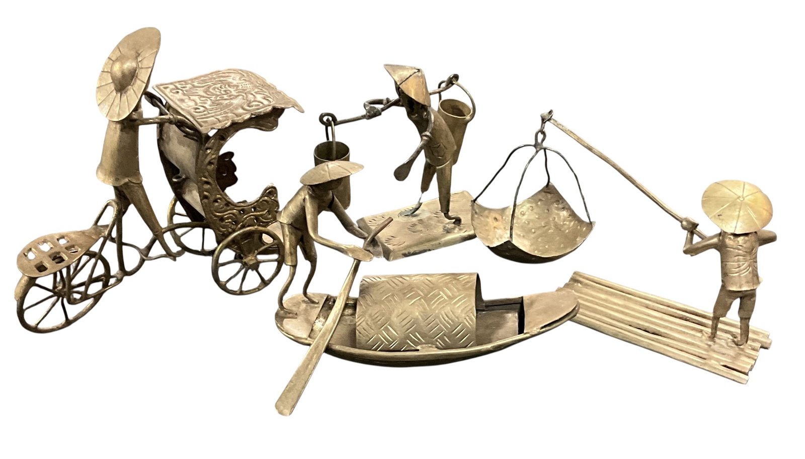 Group of Four Southeast Asian Brass Figural Sculptures: Collection of four hand-worked brass figural sculptures depicting Southeast Asian village and river scenes. Group includes a rickshaw figure, shoulder-pole water carrier, sampan boatman, and fishing f