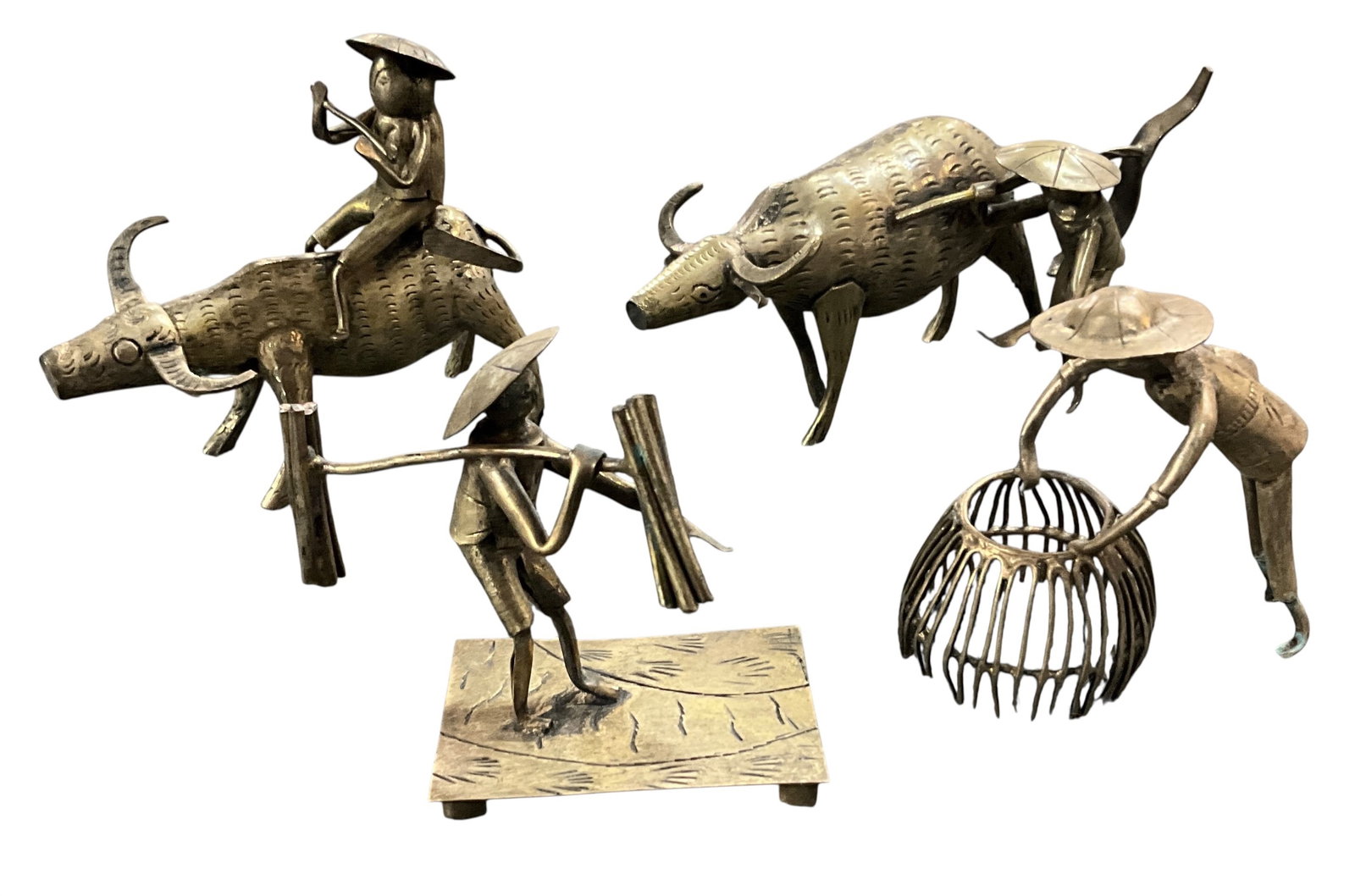 Group of Asian Brass Figural Sculptures with Water Buffalo: Decorative group of four hand-worked Asian brass figural sculptures depicting rural village scenes and water buffalo. Includes two separate water buffalo figures with mounted and attendant figures, on