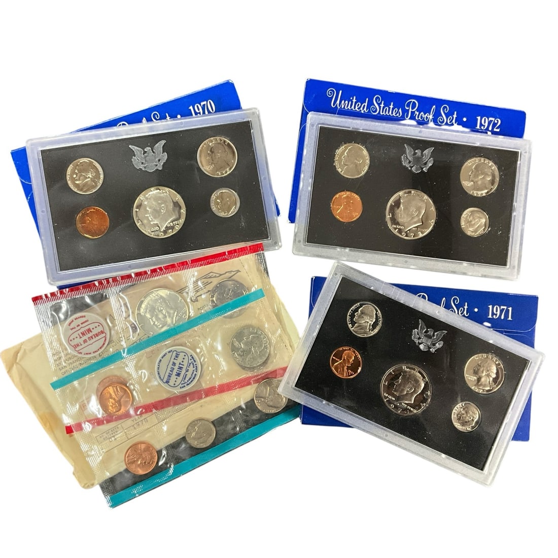 Group of 1970s U.S. Proof and Mint Coin Sets: Assorted group of 1970s United States Proof and Mint coin sets, including visible 1970, 1971, and 1972 proof sets in blue packaging, additional red insert U.S. proof sets from the 1970s, and uncircula