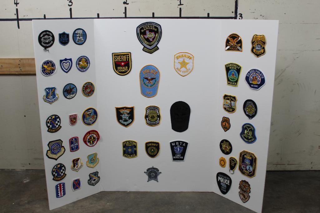 46 Various Military and Law Enforcement Patches on a Trifold Display Board (ONE$): 46 Various Military and Law Enforcement Patches on a tri-fold display board (ONE$). The patches can easily be removed from the board to be framed or gifted etc. MILITARIA AND POLICE AND LAW COLLECTIBL