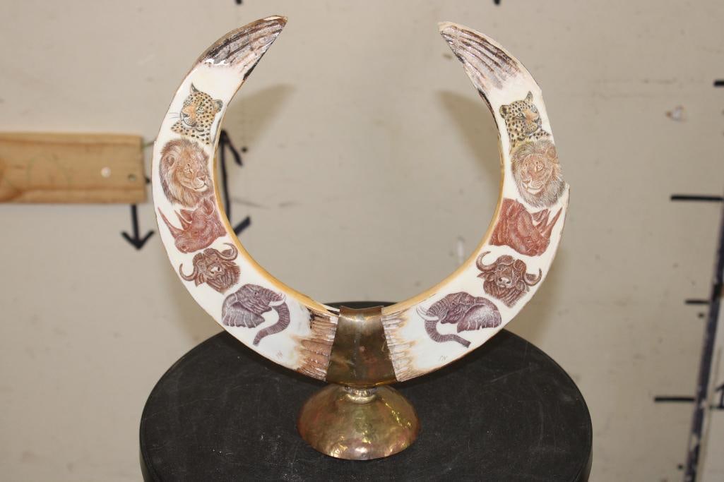 Scrimshawed HIPPOPOTAMUS IVORY Tusk signed by artist "PN" on a Brass Display Stand: 2 Scrimshawed HIPPOPOTAMUS IVORY Tusks on a Brass Display Stand. The Tusks depict a mirror image of the "Big 5" Animals that have been delicately and expertly carved. It has been signed "PN" by the ar