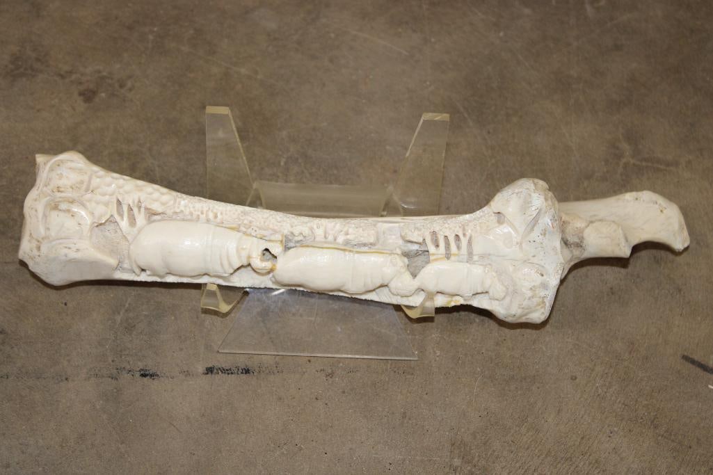 Scrimshawed HIPPOPOTAMUS Leg Bone by African artist JK ZULU: Awesome Hand-carved or Scrimshawed HIPPOPOTAMUS Leg Bone. It has been signed by African artist "JK ZULU" and is on a plastic stand. Depicted is a scene of 3 Hippo walking. It measures approximately 14
