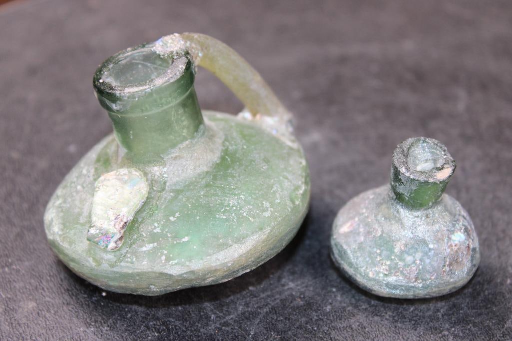 (2) Ancient Roman Glass Bottles from the Roman Empire (ONE$): 2 Ancient Roman Glass Bottles with a lovely silver patina. The smaller Bottle measures 1.25" Tall x 1.5" Wide. The larger Bottle has 1 remaining handle and measures 2" Tall x 2.75" Wide. The Total Wei