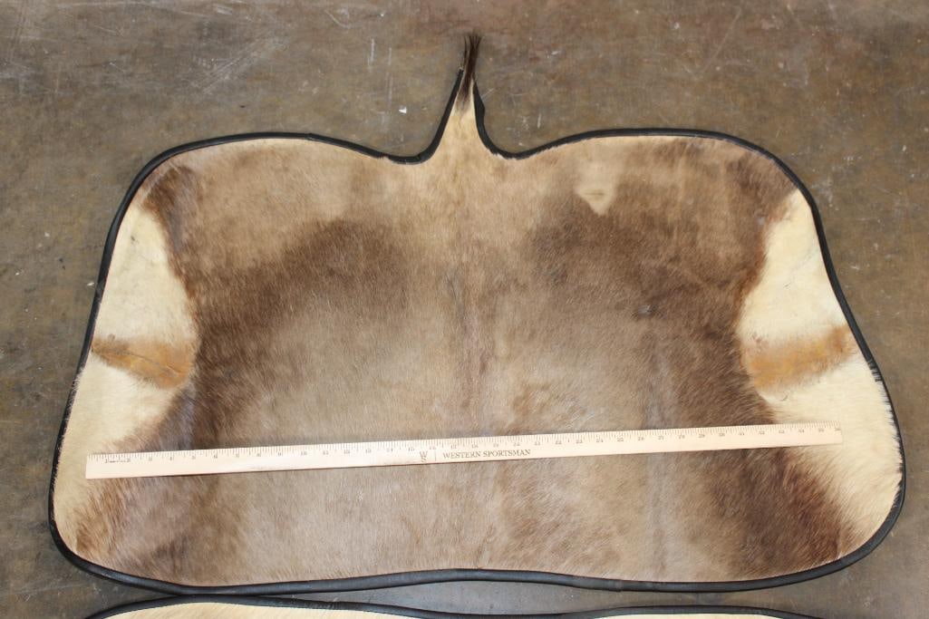 (1) BLESBOK Back Hide Rug and (1) WHITE BLESBOK Hide Rug with Carpet Backing and Leather Piping - 2