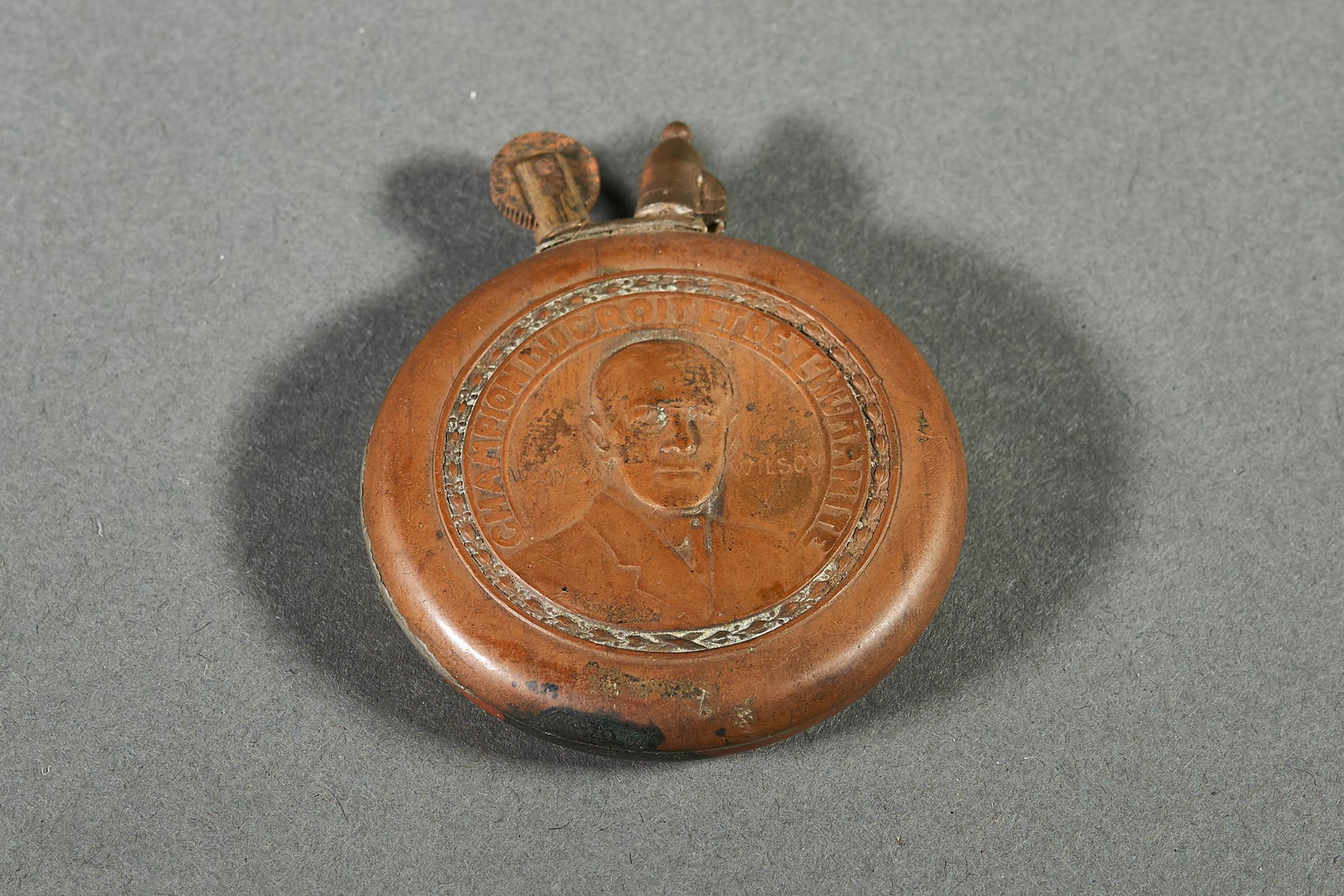 Woodrow Wilson Copper Lighter: French copper lighter, depicting president Woodrow Wilson on one side, with the words "CHAMPION DU DROIT ET DE L'HUMANITE" and an eagle on the reverse. At some point, this has been re-soldered on the 