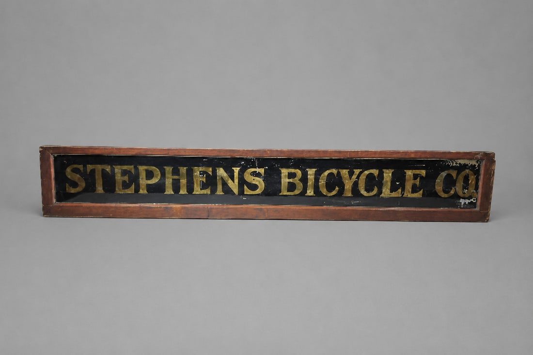 Stephens Bicycle Co. Glass and Wood Reverse Painted Gold Foil Advertising Sign: Stephens Bicycle Co. Glass and Wood Reverse Painted Gold Foil Advertising Sign Wear appropriate for its age.