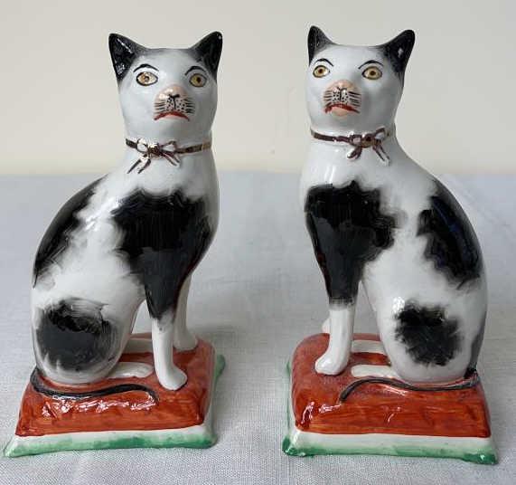 Pair English Staffordshire Cats: Black and white cats with pink noses sitting on coral pillows. Excellent condition. 3.5 X 3 X 7 tall each.