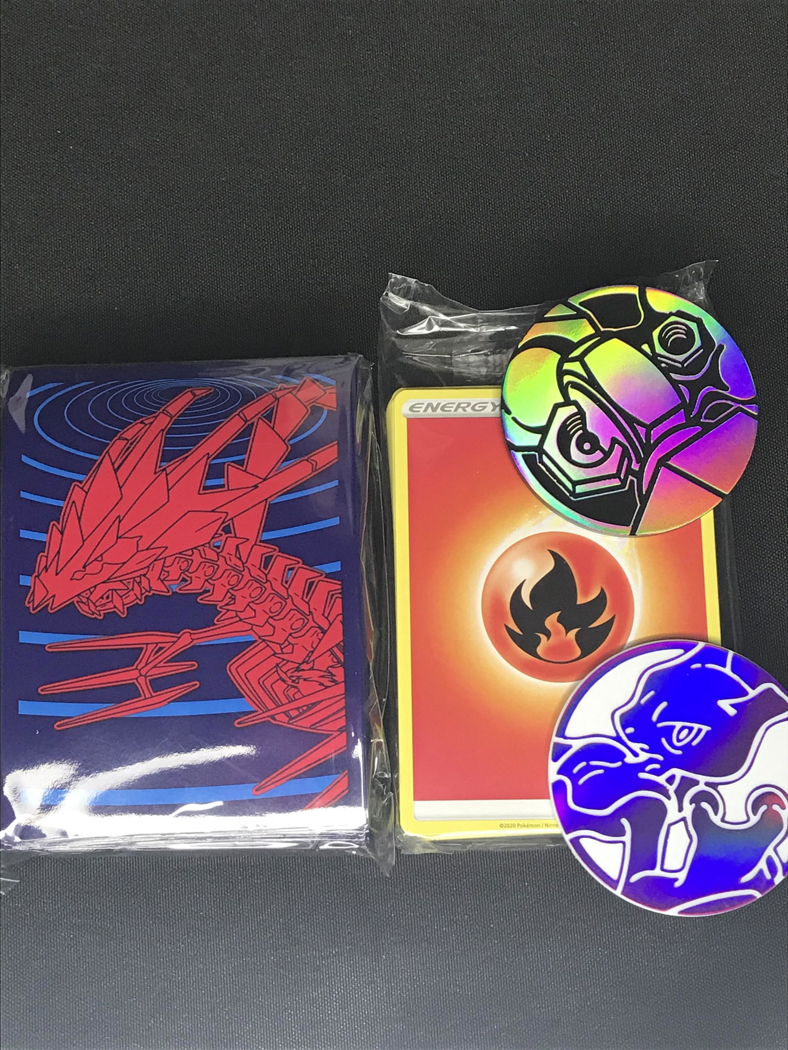 Pokemon card sleeves, pack of Energy cards, and two tokens (1 of 1)