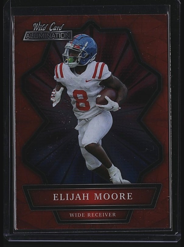 2021 Wild Card Matte MWW-20 Elijah Moore Crimson: 2021 Wild Card Autographed Elijah Moore #8 wide receiver card in raw condition. Features Moore in a white Ole Miss uniform on a red background design. Card shows crisp centering and sharp corners