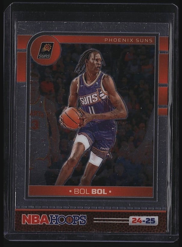 2024-25 Panini NBA Hoops #197 Bol Bol Phoenix: 2024-25 Panini NBA Hoops #197 Bol Bol Phoenix Suns raw basketball card. Features Bol Bol in his Suns uniform holding the basketball during game action. Card displays the iconic NBA Hoops design with