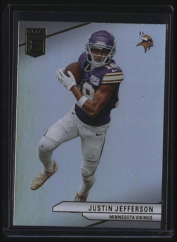 2024 Panini Donruss Elite Justin Jefferson Card: 2024 Panini Chronicles Elite Football card featuring Justin Jefferson, No. 62 of the Minnesota Vikings. This raw single showcases Jefferson in his Vikings uniform during a studio photo shoot. The