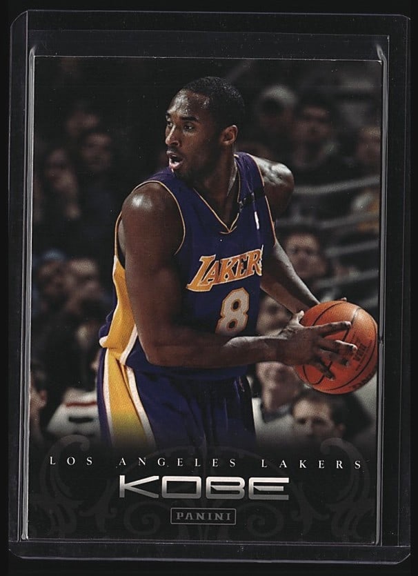 2012-13 Panini Kobe Anthology #71 Kobe Bryant: 2003 Panini Kobe card #71 featuring Los Angeles Lakers guard Kobe Bryant. Card shows Bryant in his iconic purple and gold Lakers uniform holding the basketball. The back of the card includes biographi