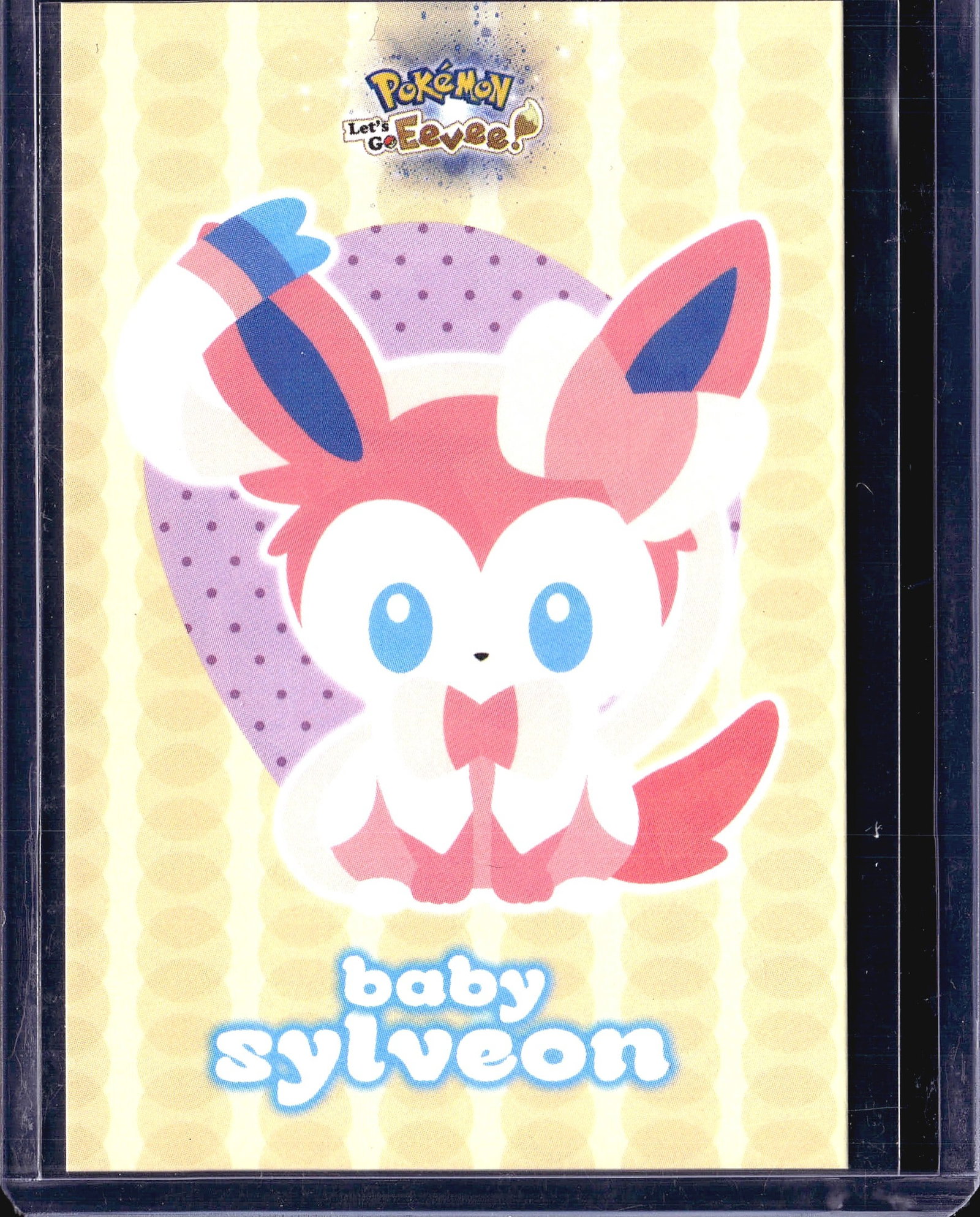 Pokemon Let's Go Eevee Baby Sylveon Trading Card: This is a raw, ungraded Pokemon trading card from the Let's Go Eevee series, featuring Baby Sylveon artwork. The card displays the distinctive pink and white coloring characteristic of the Sylveon