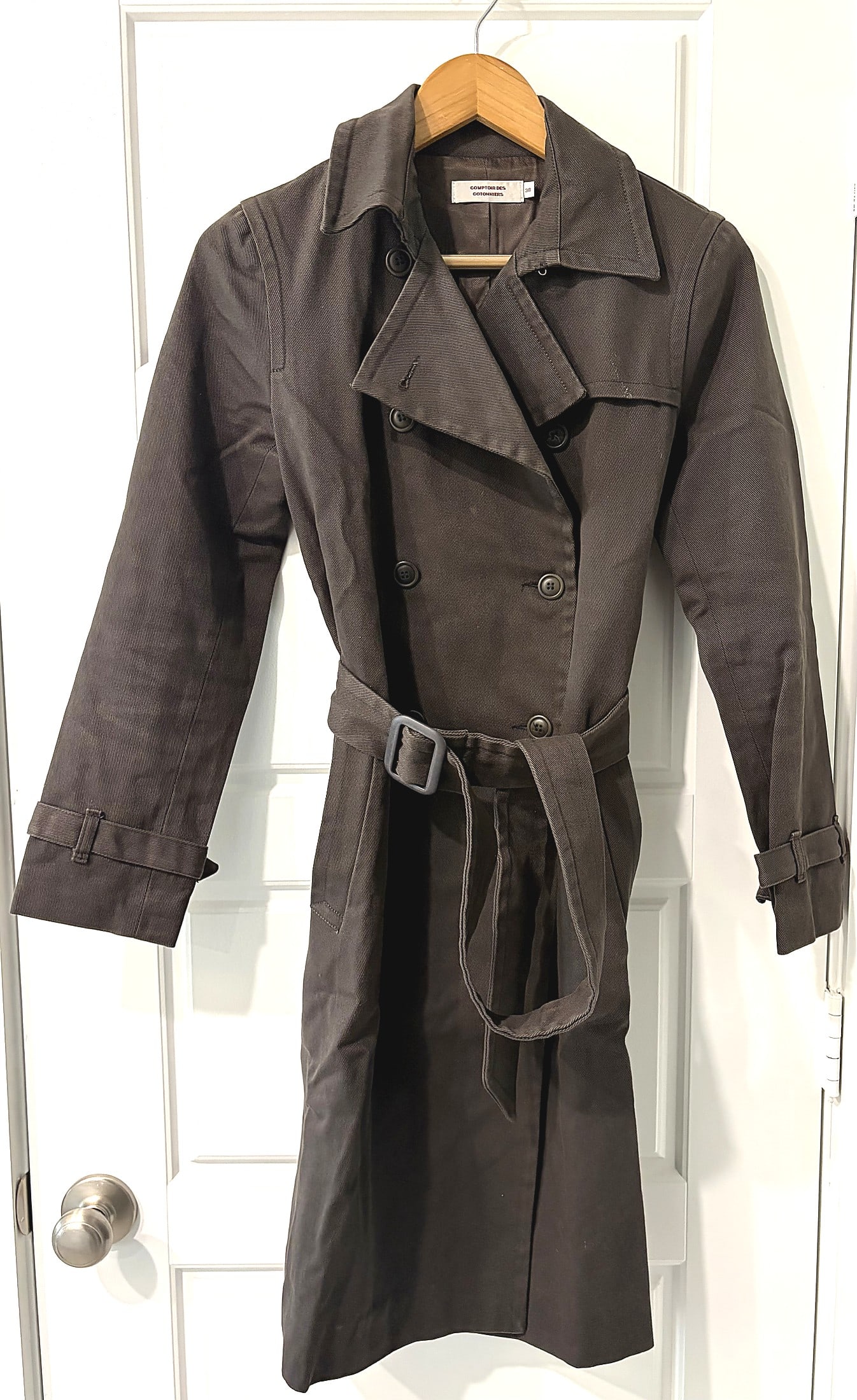 Comptoir des Cotonniers Dark Brown Belted Trench: This is a Comptoir des Cotonniers double-breasted trench coat in a dark brown/charcoal tone. The coat features a classic notched lapel with storm flap, double-breasted button closure, a matching