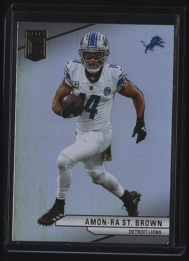 2024 Panini Donruss Elite #87 Amon-Ra St. Brown: Raw single from 2024 Panini Donruss Elite Football featuring Amon-Ra St. Brown of the Detroit Lions, card #87. St. Brown is shown in white Detroit Lions uniform on the front. The card back includes hi