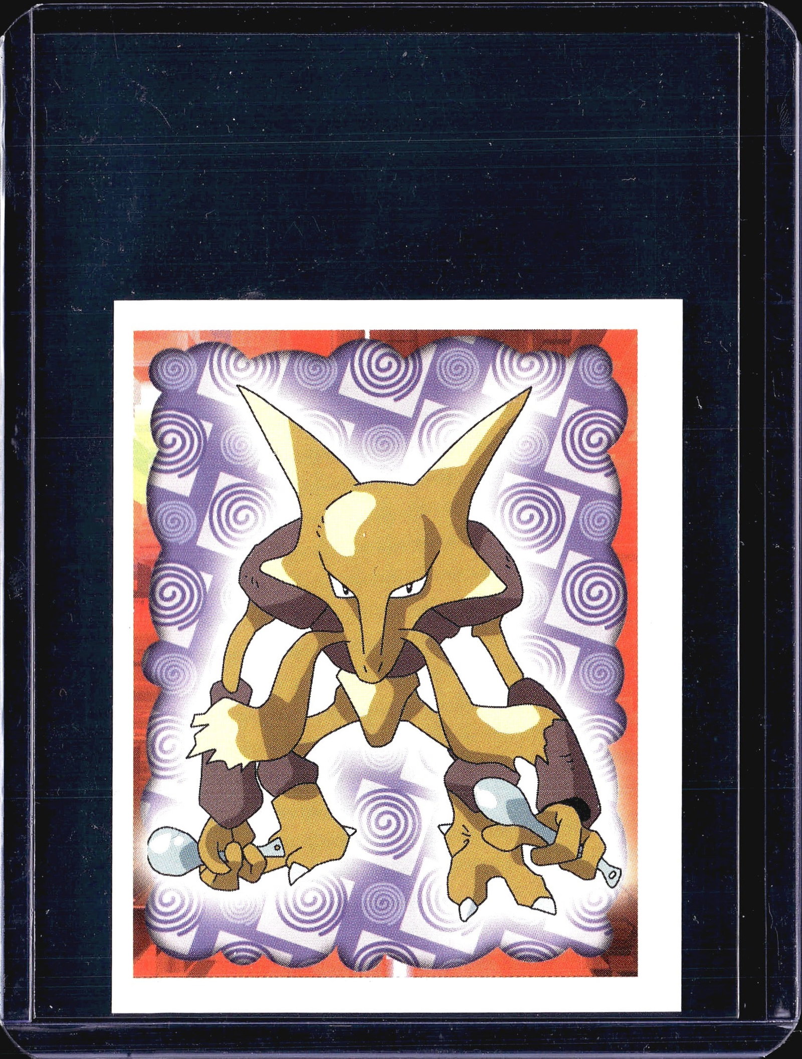 1999 Pokemon Merlin Collection Sticker #65: This is a 1999 Pokemon Merlin Collections sticker numbered #65, featuring Alakazam alongside what appears to be its pre-evolutions Abra and Kadabra in a dynamic psychic-themed illustration with