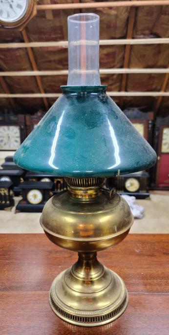 Antique Oil Table Lamp: Description: This lot includes an antique oil table lamp. Lamp features a green glass shade and brass base. Condition: Lamp is in good condition. Shade has minor "flea bite" chips around the edges. Lo