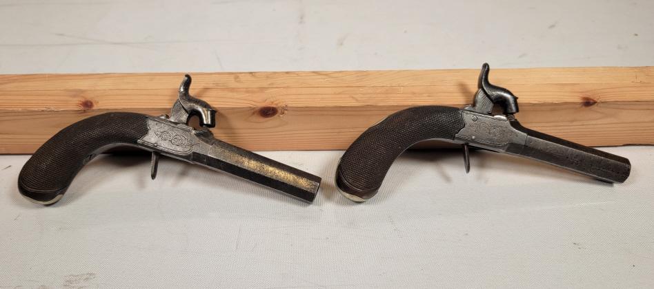 Pair of Antique Dueling Pistols - By Deanes London: Description: This lot includes a matched pair of antique (Pre-1898) dueling pistols. The pistols are made of Wood and Steel, with engravings throughout the entirety of the gun. The grip is stippled wo