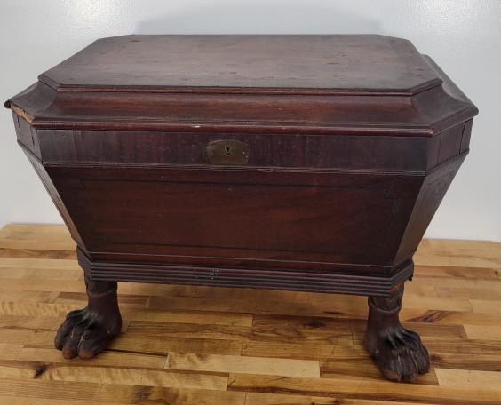 19th C. George III Mahogany Wine Cooler: Description: This lot includes a 19th century wine cooler with a Mahogany veneered cabinet and heavy cast lions paw feet. The cooler is tin lined with dividers inside. Condition: Offered exactly as fo