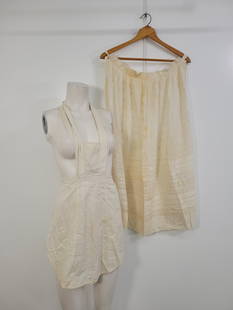 Pair Of Vintage Aprons: Description: two white vintage aprons. Short one wraps around neck, has some staining on front and neck tie (see photos) long one has some staining and discoloration (see photos)Measurements: one size