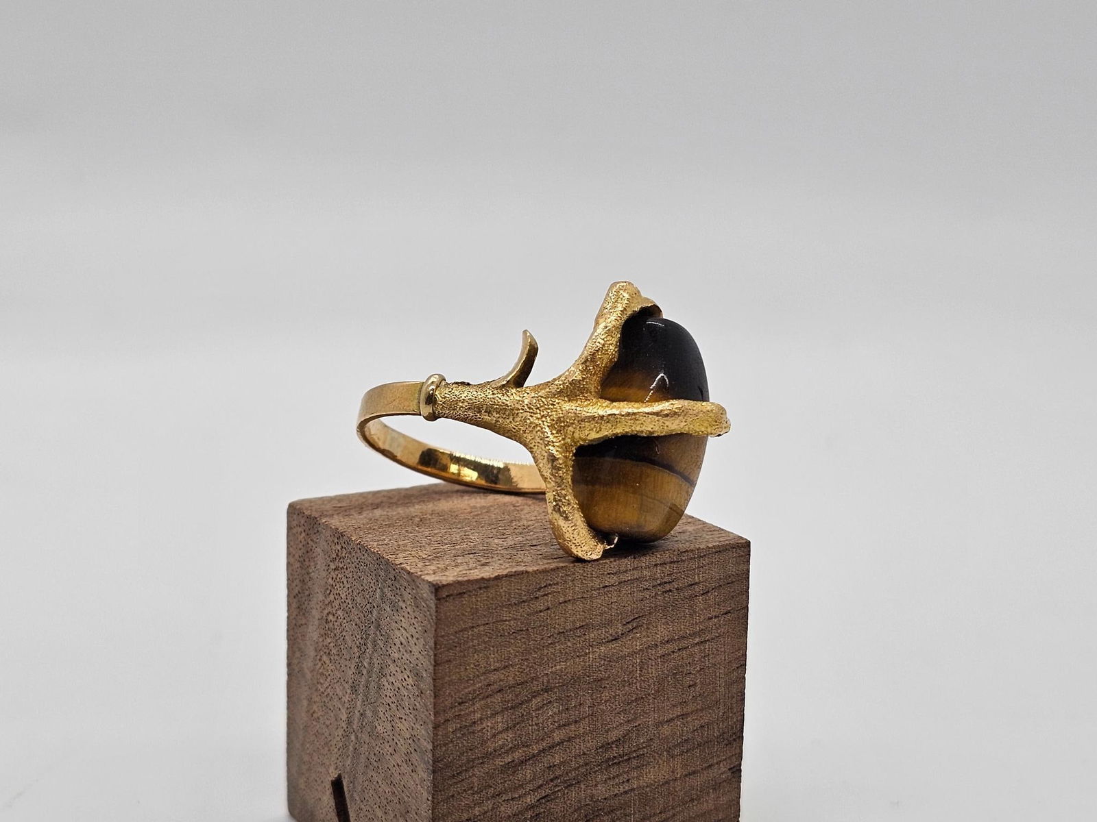 18K Yellow Gold & Tiger-eye "Talon" Ring: This ring features a polished Tiger-eye stone at the center being held in by figural bird talons. Set into 18k yellow gold as marked on the inside, this ring appears to be vintage in age. Ring size is