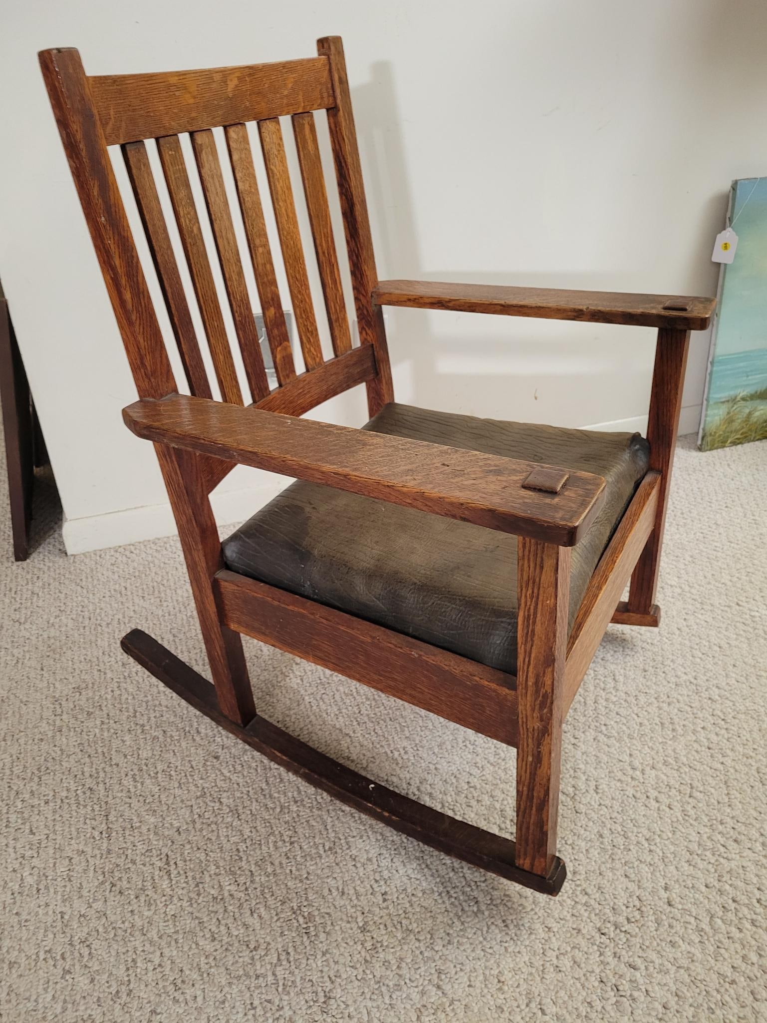 Original Early 20th C. Stickley Rocking Chair: Marked on the bottom with the Stickley tag. Original finish in perfectly worn condition as expected with age. Original leather seat, early 20th centuryMeasurements: 28"L x 25.5"W x 34.5"HTransport Fee