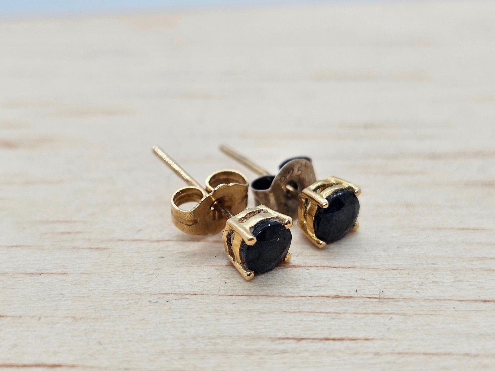14K Yellow Gold & Natural Sapphire Stud Earrings: This lot includes a pair of 14k yellow gold stud earring each with a small Nature sapphire cut stone at the center. The earrings are in good condition with minor expected ware from age and use. See ph