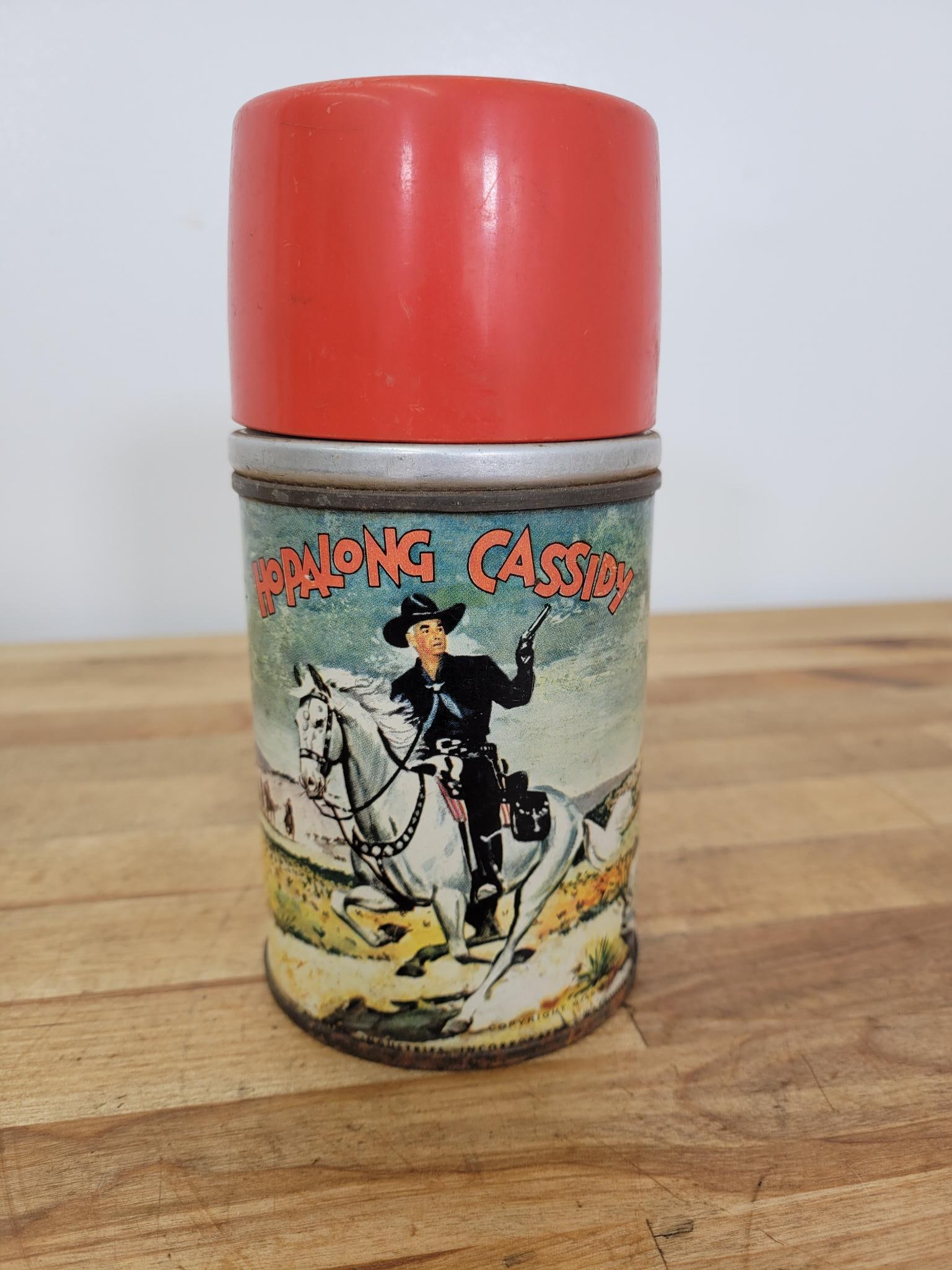 Hopalong Cassidy Thermos: vintage Hopalong Cassidy thermos featuring colorful graphics of the iconic cowboy on horseback. This collectible item is in good overall condition with expected wear from age and use