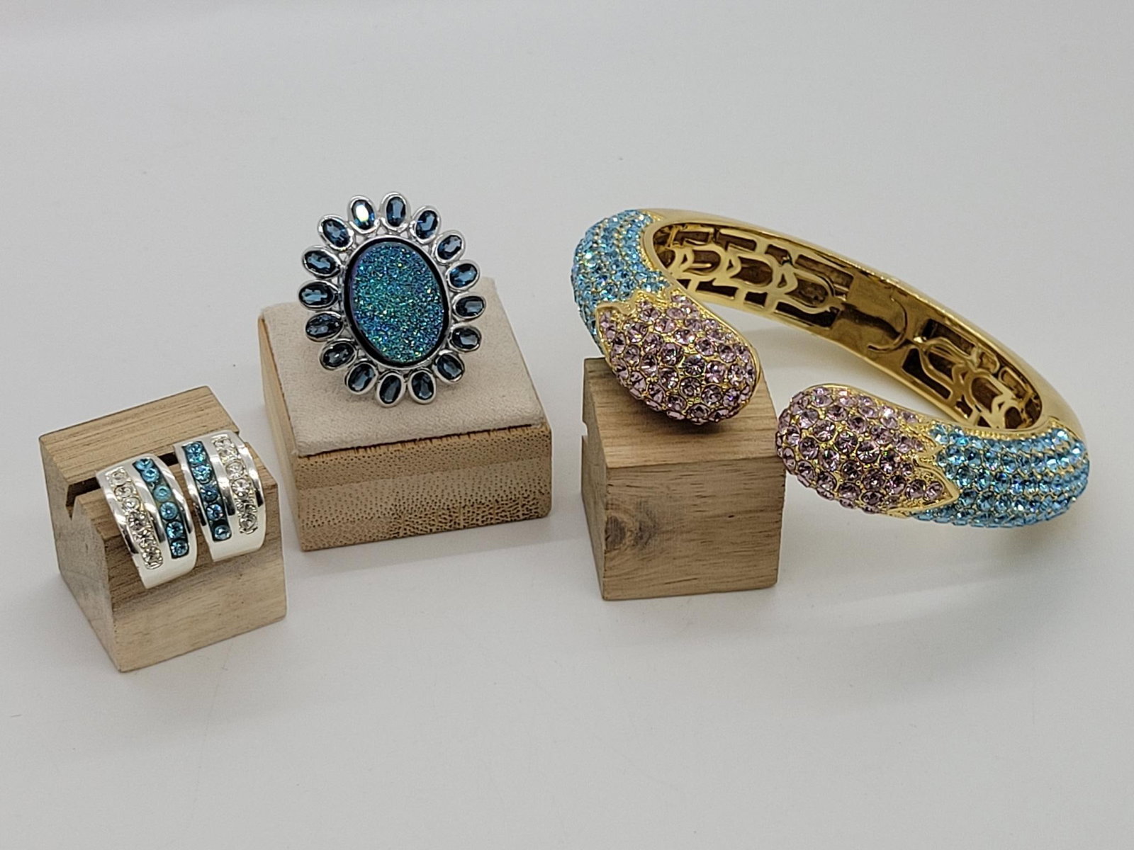 Pink And Blue Sparkle Set: Description: this trio of glitz will add a touch of glamor to any event. Sterling silver (12.4g) ring by Victoria Wieck. Gold colored blue and pink hinged bangle by Joan Boyce. Earrings by Roman