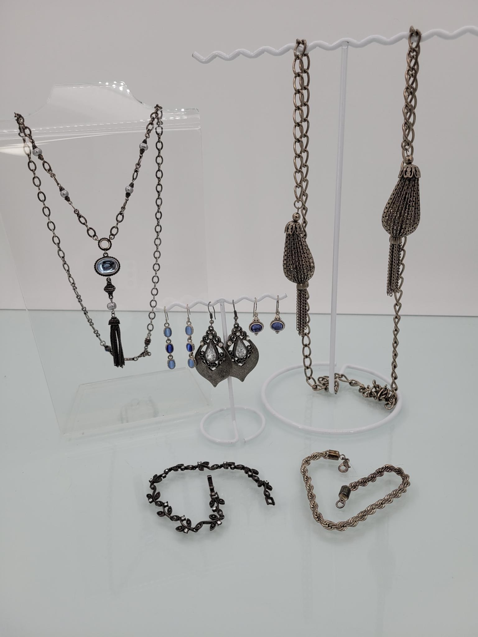 Silver Toned Tassel Lot: Description: two silver toned necklaces featuring tassel details, three pairs of hanging earrings and two silver toned bracelets