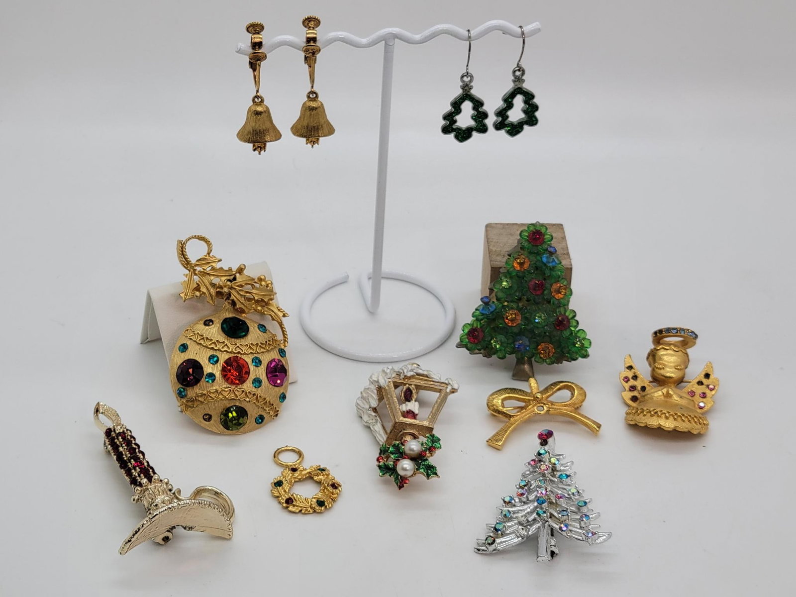 Sparkling Holiday Pins And Earrings: Description: lot includes seven holiday themed pins, a wreath pendent, Christmas tree hanging earrings, and gold toned bell clip on earrings