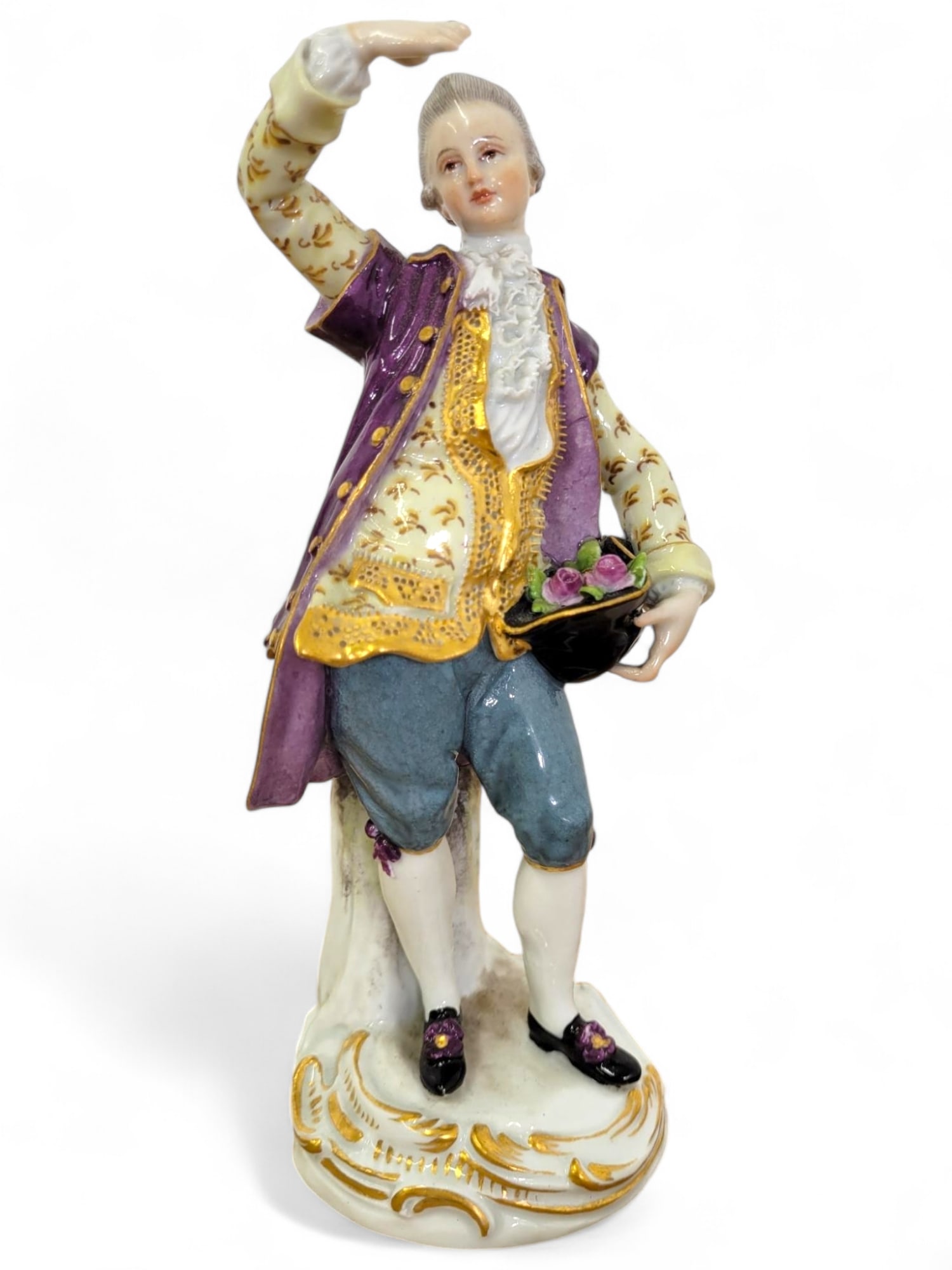 Meissen 1910 Anniversary Mark Figure of a Man: Meissen Porcelain figurine of a gentleman dressed in 18th-century attire, holding a hat and bouquet. The figurine is hand-painted with gold accents and is in good condition with minor wear to the pain