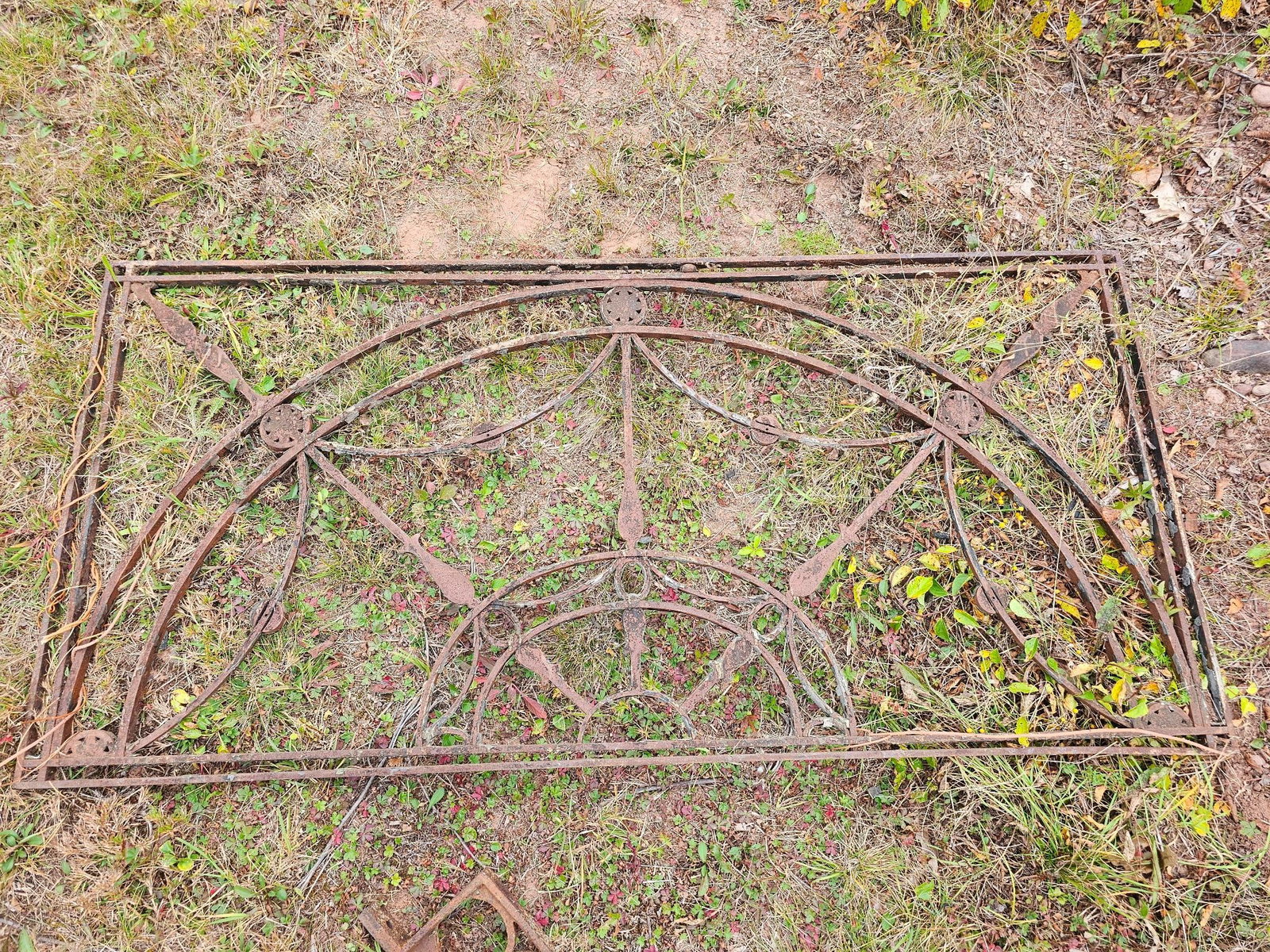 Antique Iron Gate with Ornate Design: Ornate antique iron gate with a decorative design, featuring circular and arched elements. Shows surface rust and wear consistent with age. Offered in estate-found condition. Please see photos for mor