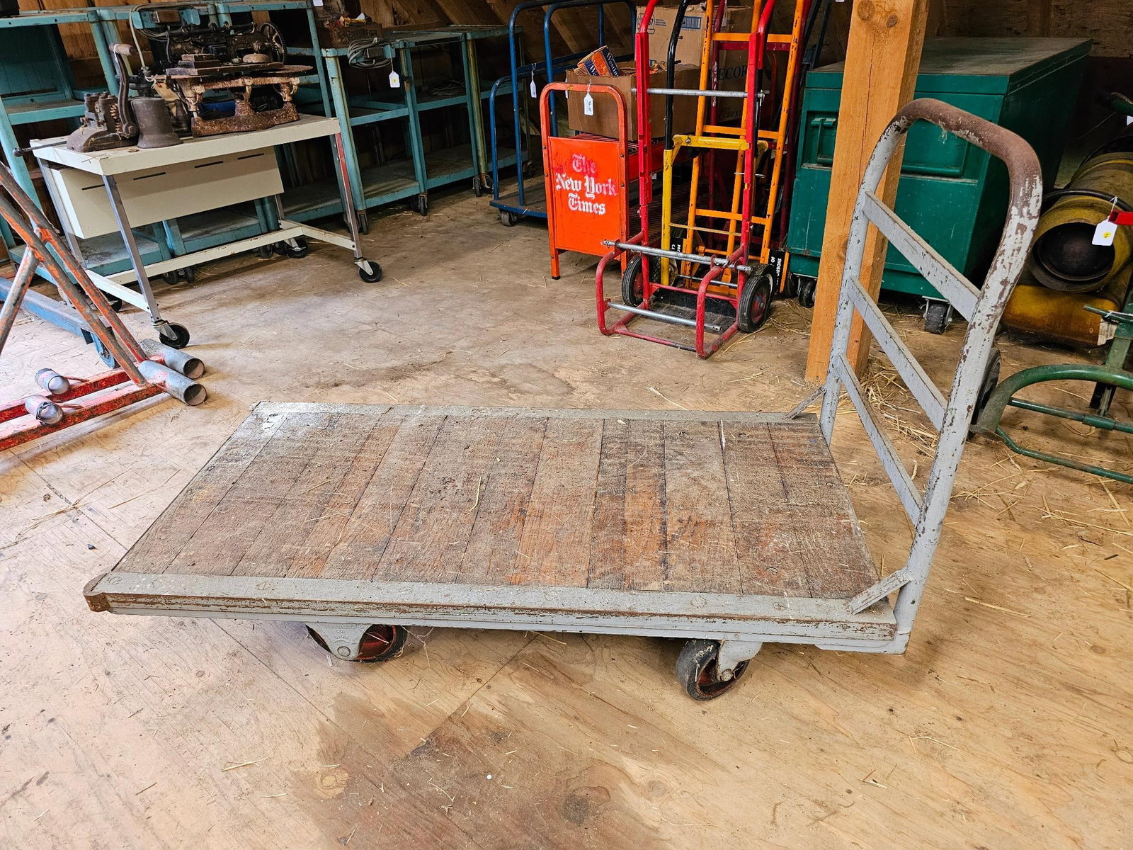 Industrial Flatbed Cart with Wooden Platform: An industrial flatbed cart with a sturdy wooden platform and metal frame. Shows signs of wear and use consistent with its age. Offered in estate-found condition. Please refer to photos for more detail