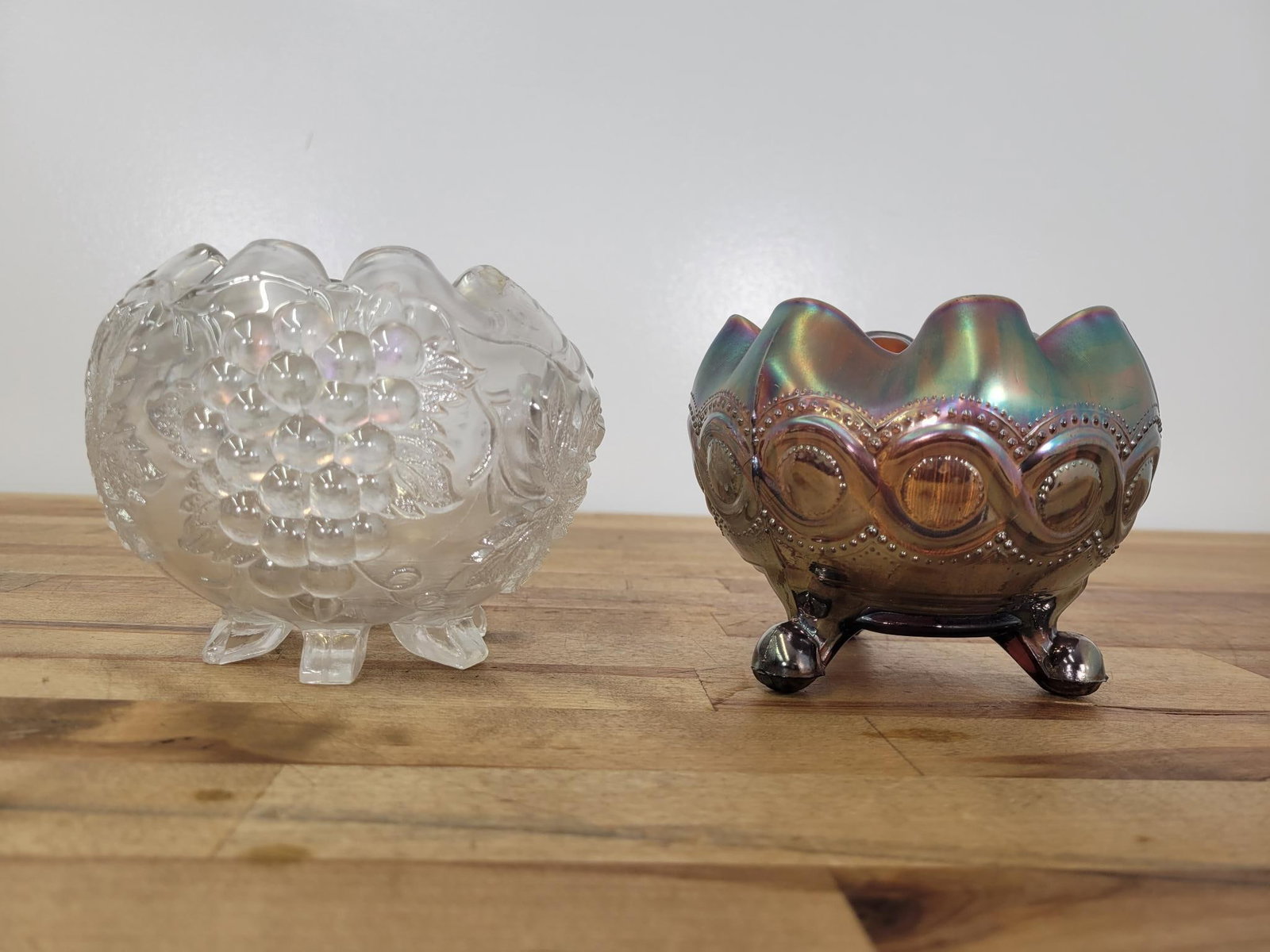 Pair Of Footed Round Ruffled Bowls: Maker: Northwood, Dugan Pattern: Amethyst beaded cable three footed round ruffled bowl, clear iridescent grape delight footed ruffled bowl Condition Issues (If Any): Amethyst bowl has what could be an