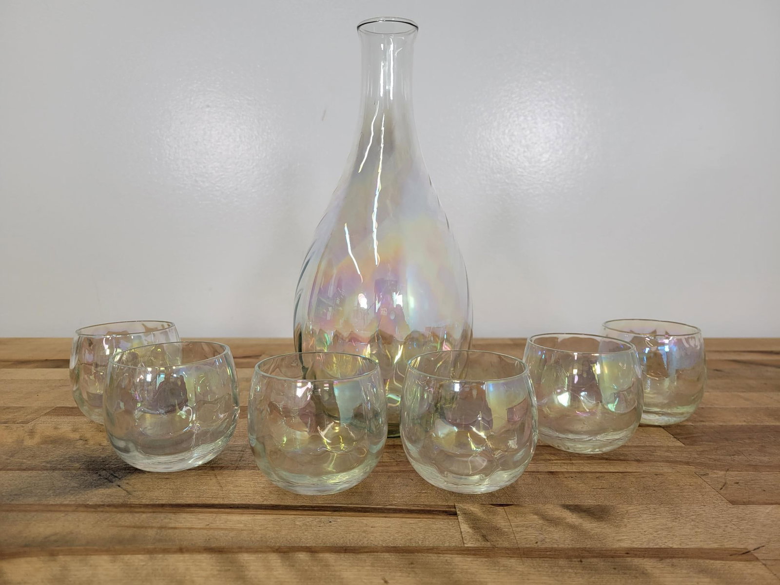 Iridescent Ribbed Spiraled Carafe & 6 Glasses: Maker: Unknown Pattern: Clear iridescent rainbow ribbed spiral carafe and 6 ribbed short glasses Condition Issues (If Any): some flea bite chips on rim of one glass, possibly from manufacturing, not s