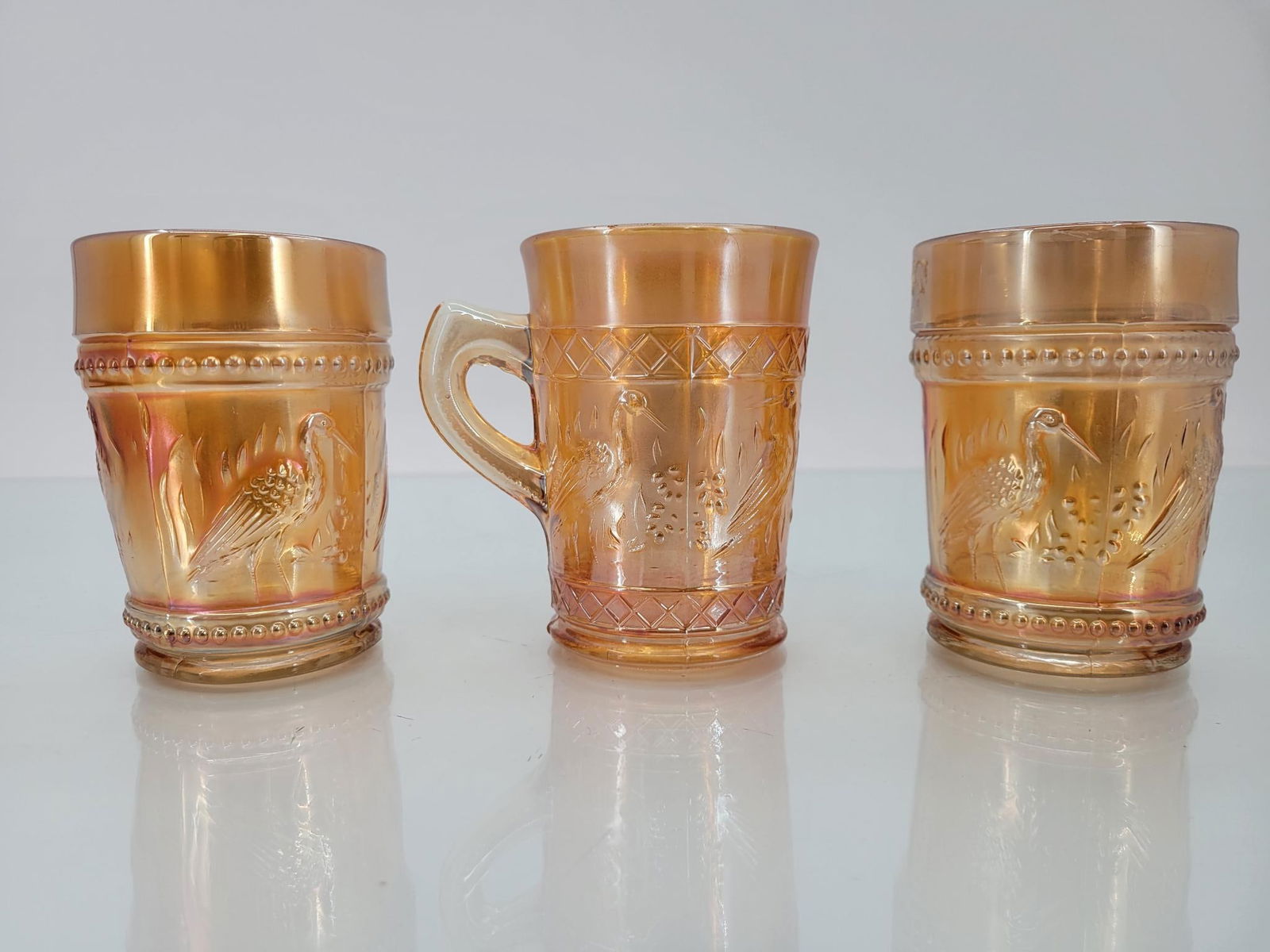 3 Dugan Marigold Stork & Rushes Lattice/Bead Cups: Maker: Dugan Pattern: Marigold stork and rushes lattice band (handled cup) or bead band cups Condition Issues (If Any): Some sticker residue Handled cup measurements: 4 "L x 3 "W x 4 "H Condition <